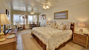 A bedroom with a large bed, a ceiling fan, a desk with a lamp, and a chair. - 146 The Shores (Panama City Beach)