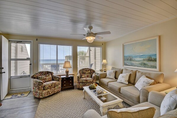 A living room with a ceiling fan, a sofa, two armchairs, a coffee table, and a painting on the wall.
