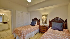 A bedroom with two beds, a dresser, a mirror, and a ceiling fan. - Calypso Resort by BBG (Panama City Beach)