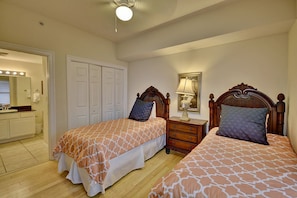 A bedroom with two beds, a dresser, a mirror, and a ceiling fan. - Calypso Resort by BBG (Panama City Beach)