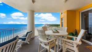 Een balkon met witte meubels, een ronde tafel en uitzicht op de oceaan.