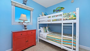 Ein Kinderzimmer mit Etagenbett, Kommode, Lampe und Fenster mit Blick.
