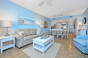 A modern living room with a sofa, coffee table, and a dining area with chairs and a table. - Sterling Breeze 2001 (Panama City Beach)