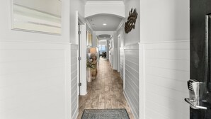 A hallway with white walls, a wooden floor, and a black door with a keypad lock. - Sol Mate Unit C304 (Santa Rosa Beach)