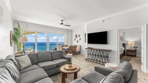 A modern living room with a gray sectional sofa, a round wooden coffee table, and a flat-screen TV mounted on the wall. - Sol Mate Unit C304 (Santa Rosa Beach)