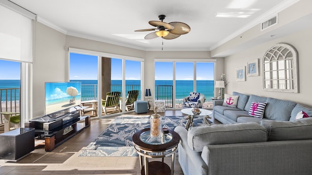 A spacious living room with a large TV, comfortable seating, a ceiling fan, and a view of the ocean. - Tidewater 317 (Panama City Beach)