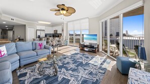 A spacious living room with a sofa, coffee table, and a large TV. - Tidewater 317 (Panama City Beach)