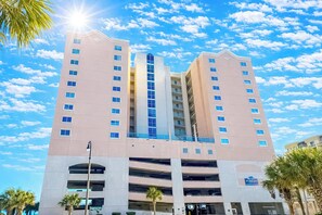 A multi-story hotel with a central atrium, multiple balconies, and a parking garage below.