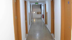A long, narrow hallway with wooden doors on both sides, a tiled floor, and a ceiling with recessed lighting. - Famous Hotel Marmaris (Marmaris)