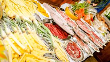 Un bufé con diversos alimentos, incluyendo piña, carne y otros platos.