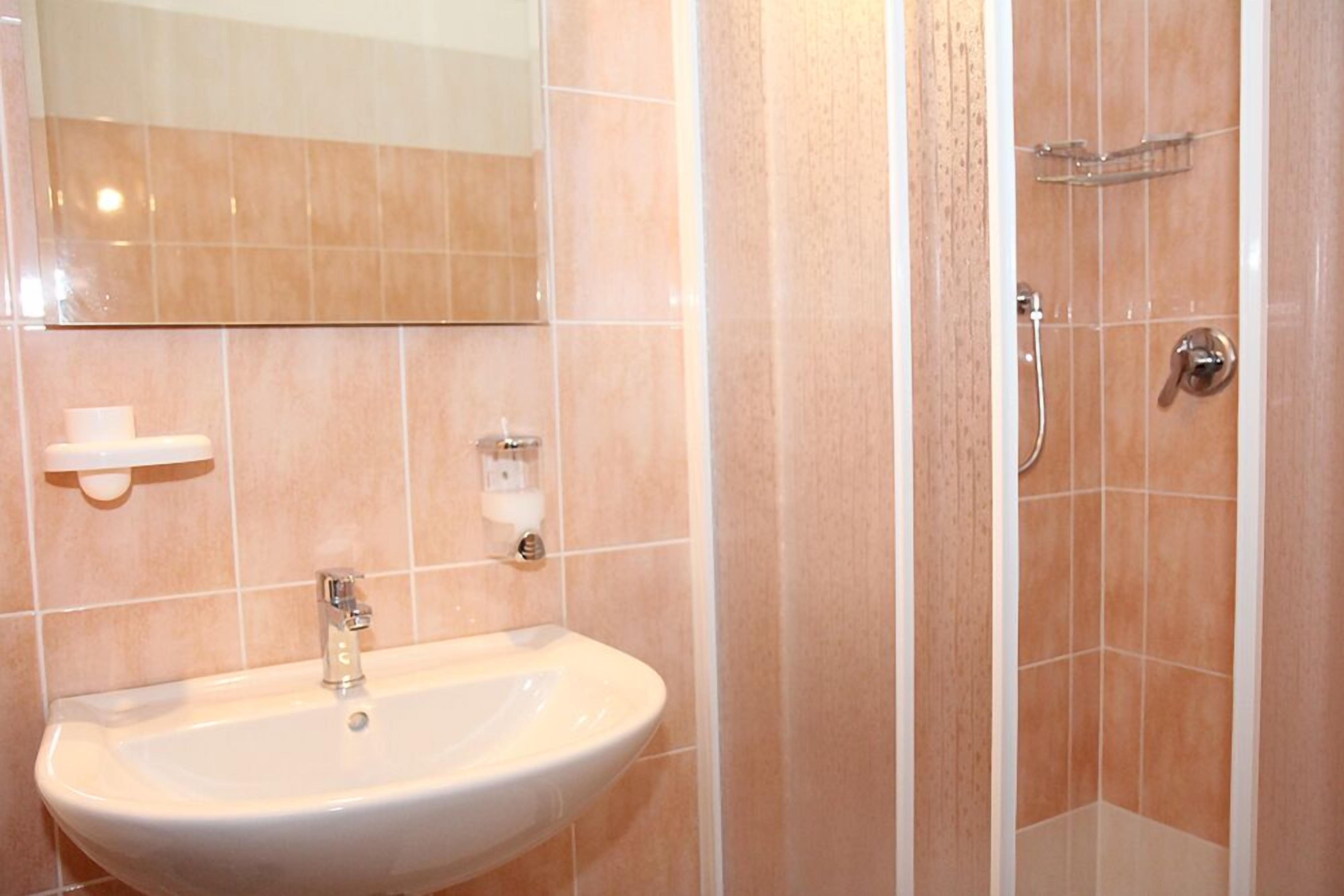 A bathroom with a sink, mirror, and shower.