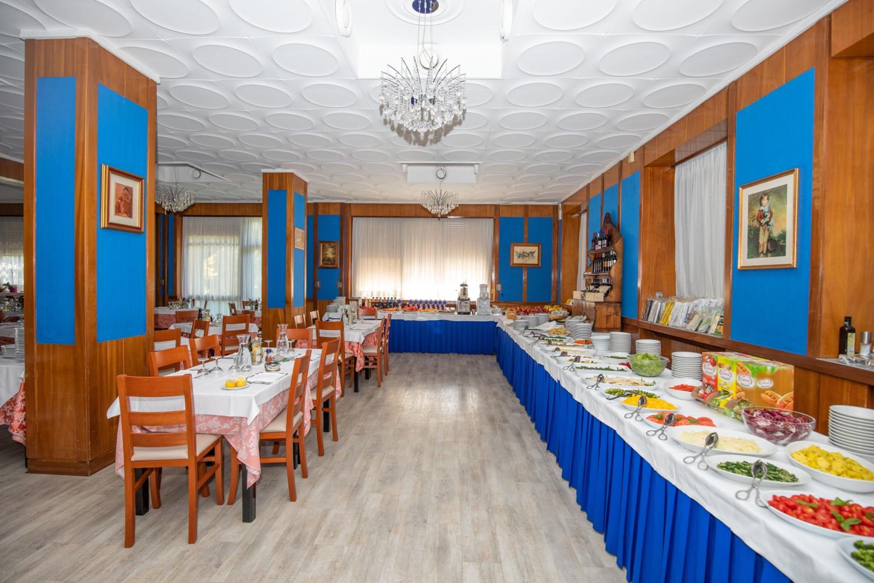 Une salle de banquet avec une longue table recouverte d’une nappe bleue, entourée de chaises en bois.