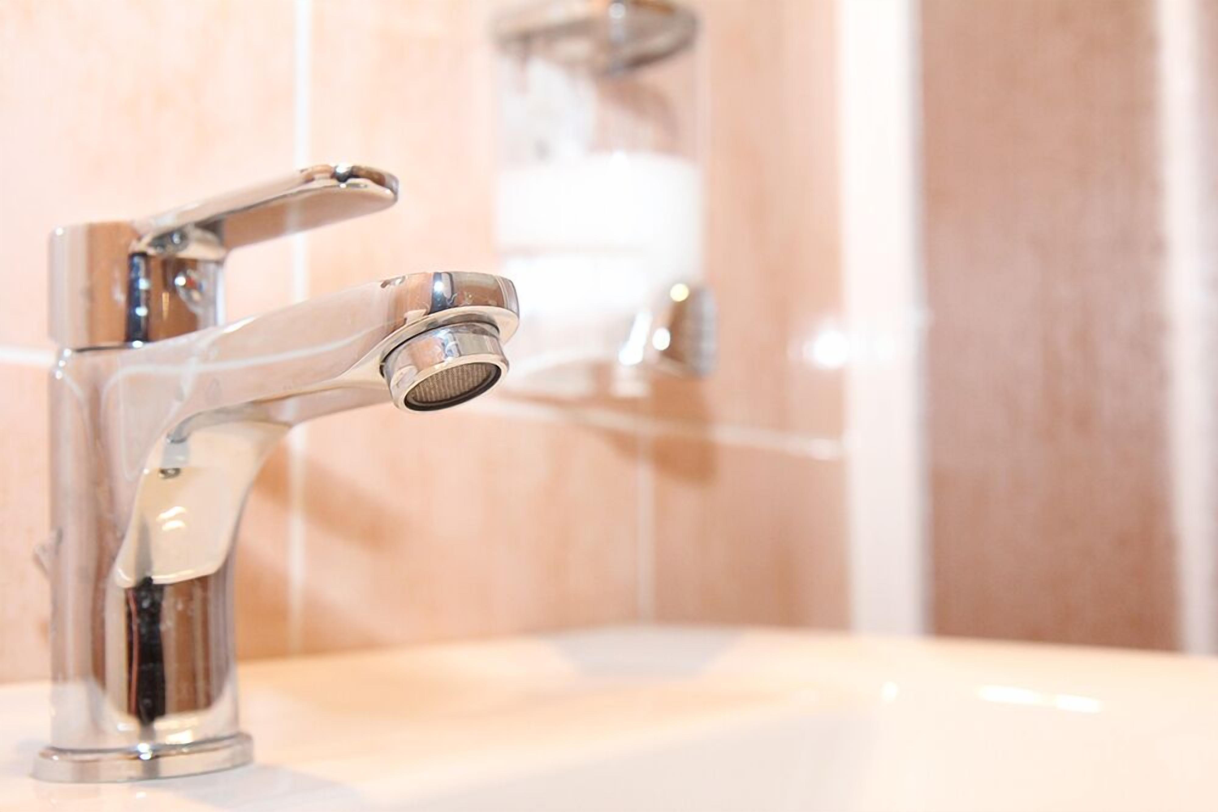 Une salle de bain moderne avec un robinet chromé et un distributeur de savon en verre transparent.
