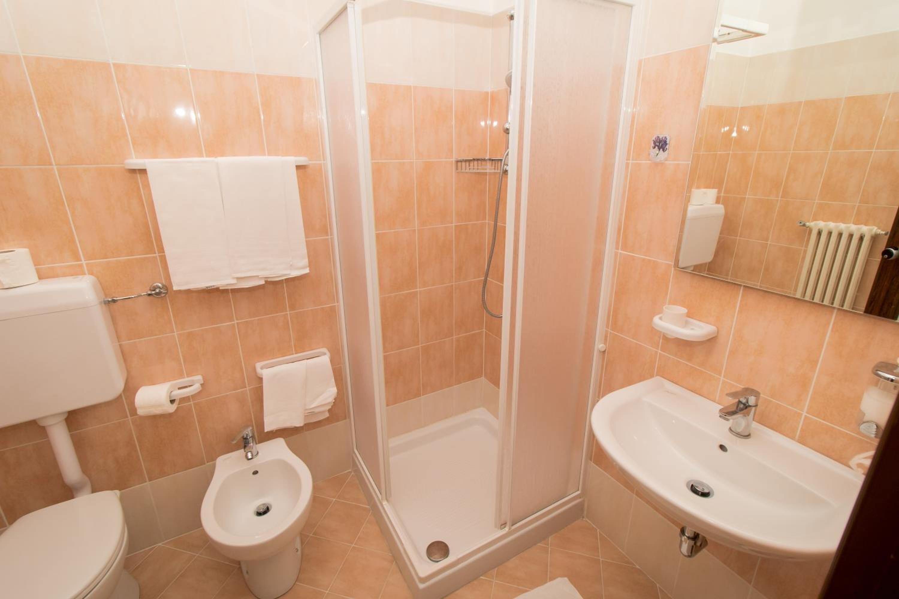 Un baño con inodoro, bidé, ducha y lavamanos.