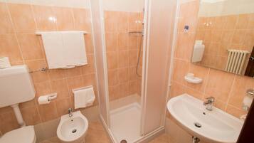 Un baño con inodoro, bidé, ducha y lavamanos.