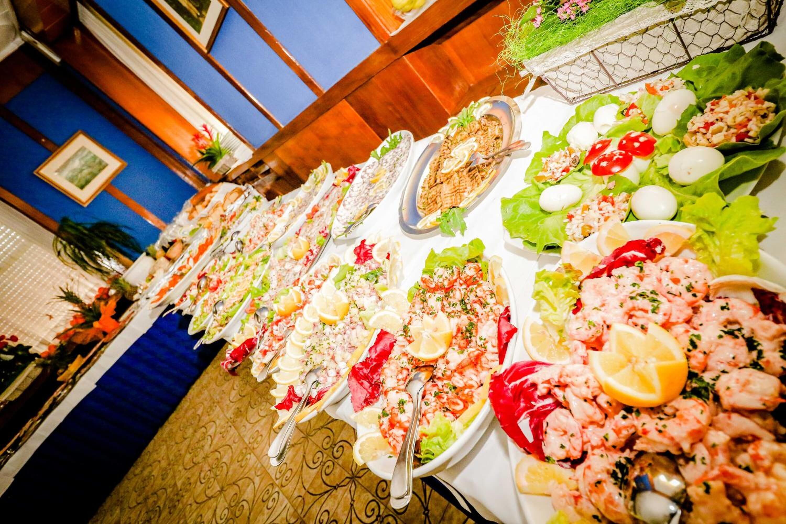 A long table with various seafood dishes, including shrimp and salads, in a restaurant setting.