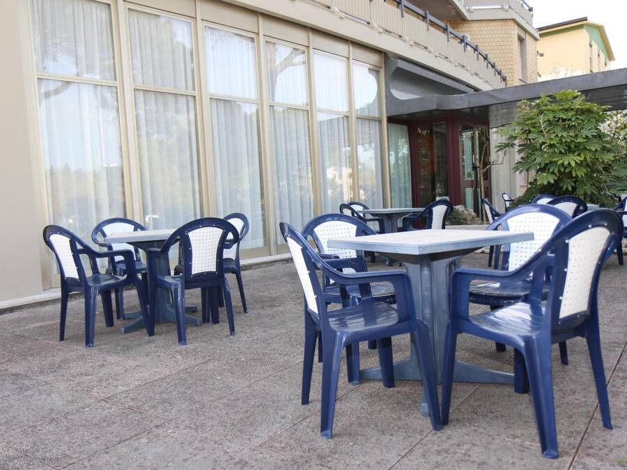 Outdoor seating with tables and chairs, a building with large windows, and a covered area.