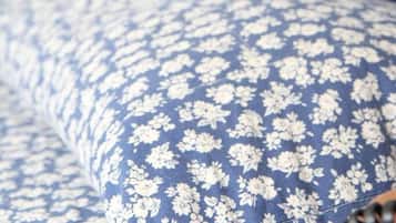 A bed with a blue floral pattern and a headboard.