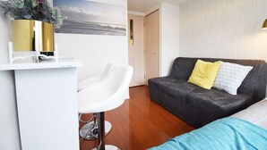 Una sala de estar moderna con un sofá gris, una silla blanca y una mesita pequeña con un jarrón dorado.