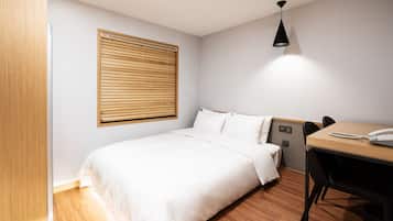 A neatly arranged hotel room with a bed, a desk, and a chair.