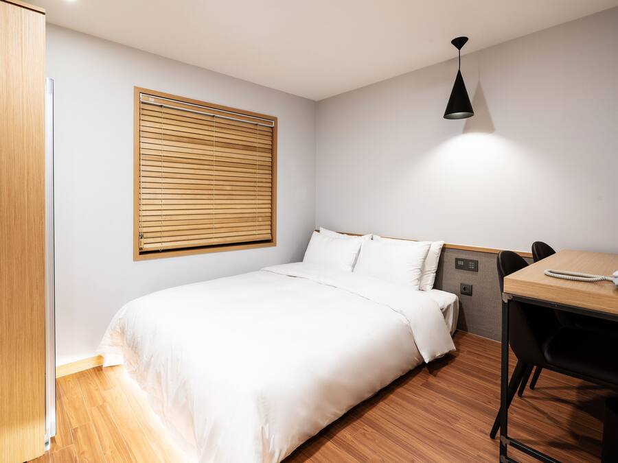 A neatly arranged hotel room with a bed, a desk, and a chair.