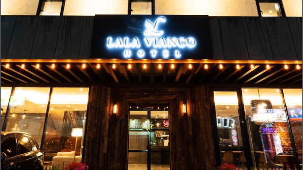 Das äußere Erscheinungsbild des Hotels Lala Vianco mit einer auffälligen, beleuchteten Signatur, einem überdachten Eingang und einer gut beleuchteten Fassade.