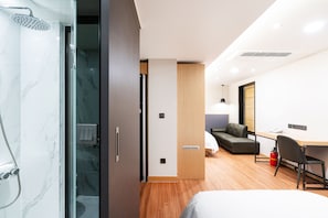 Una habitación de hotel moderna con ducha, escritorio, sofá y cama.