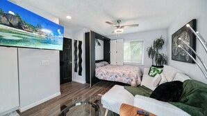 A compact living space with a bed, a sofa, a TV, and a ceiling fan. - Escape to Kokomo Bay,  Escape to Paradise (Fort Myers)