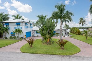 A modern building with a blue and white facade, surrounded by well-maintained grass and palm trees.
