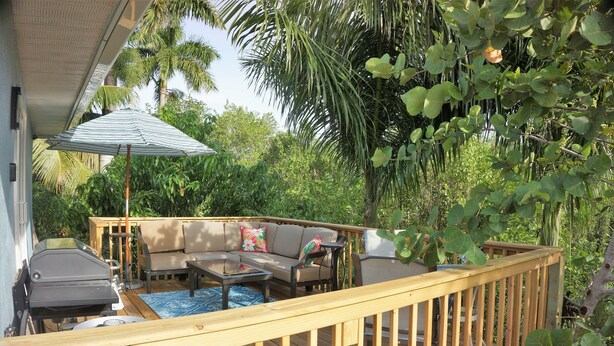 A wooden deck with a barbecue grill, a sofa, and a table. - Escape to Kokomo Bay,  Escape to Paradise (Fort Myers)