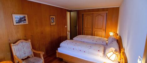 A bedroom with a wooden bed, a chair, and a small table.