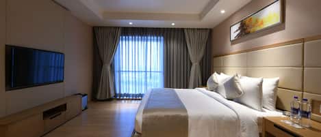 A modern hotel room with a large bed, a flat-screen TV, and a window with curtains.