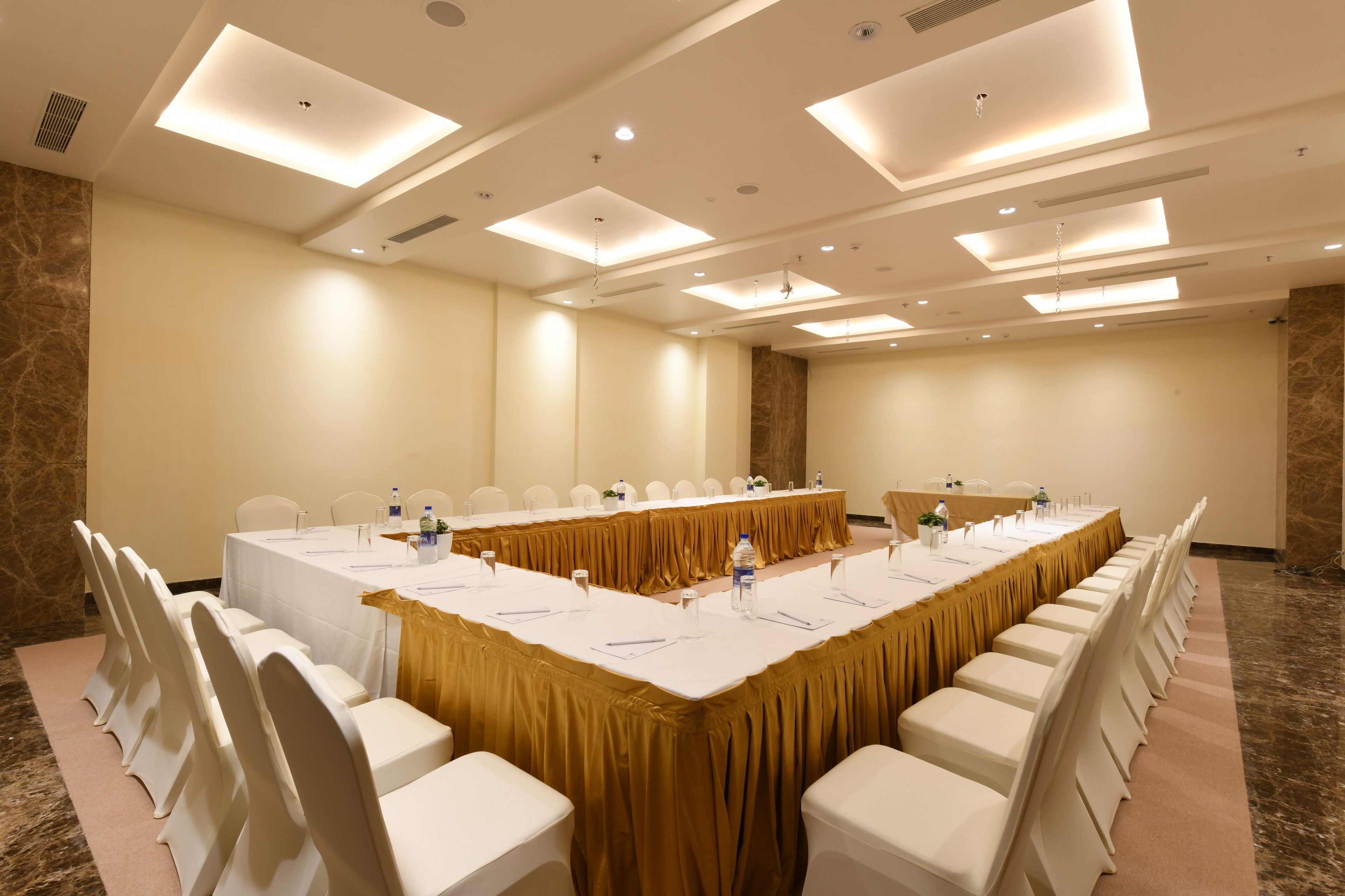 A conference room with a long table, white chairs, and a gold tablecloth.