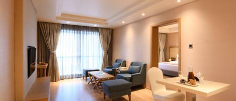 A hotel room with a seating area, a dining table, and a bed.