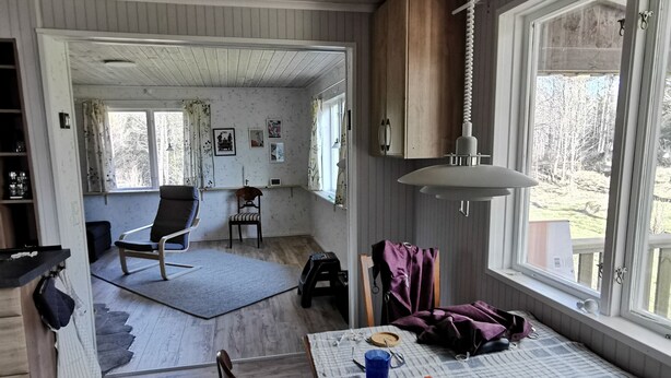 Una habitación acogedora con una mesa de comedor, sillas, techo de madera y una ventana con vistas al exterior.