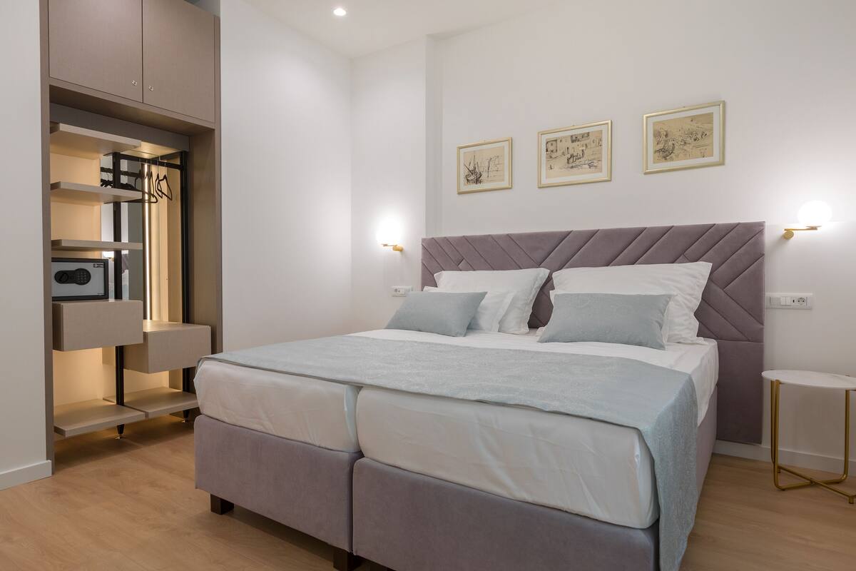 A modern bedroom with a bed, built-in wardrobe, and bedside tables.