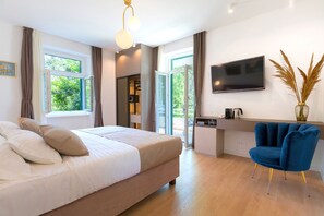 A modern bedroom with a bed, a desk, and a chair. There is a TV on the wall and a window with curtains. - Luxury Rooms Green Park (Split)