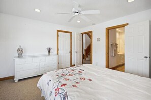 Un dormitorio con cama, cómoda y dos puertas que dan a otras habitaciones.