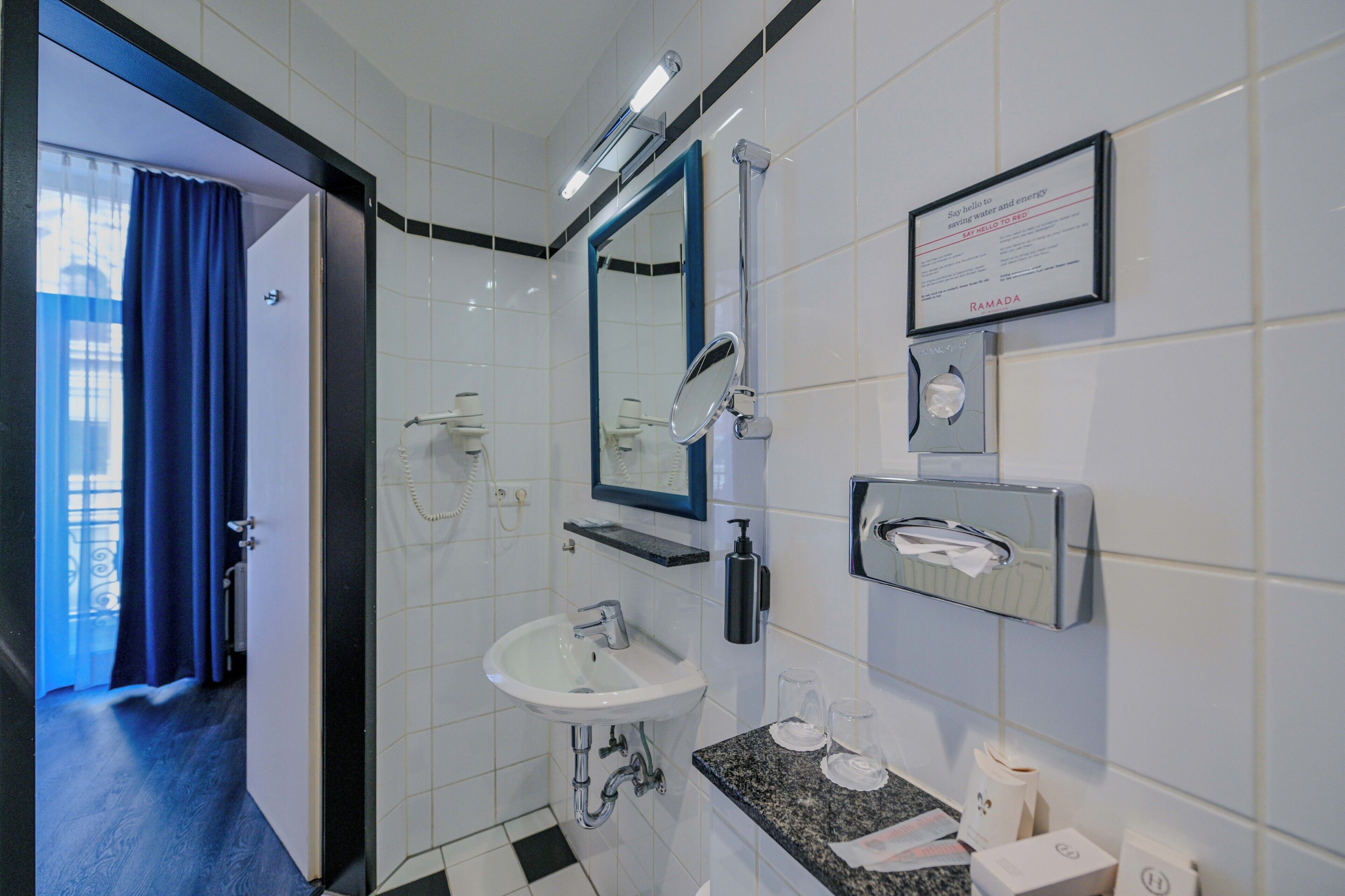 Un baño moderno con lavamanos, espejo y dispensador de toallas.
