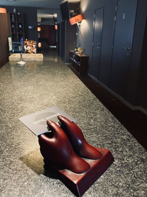 A hotel lobby with a reception desk, a seating area, and a counter with a menu. - Hotel Bornem (Bornem)