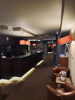Un moderno vestíbulo de hotel con recepción, zona de estar y bar.