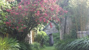 A garden with a stone structure, lush greenery, and flowering plants. - On a 3h property, in the heart of the forest, the gites du lety await you. (Perret)