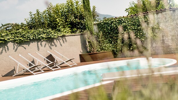 A rooftop pool with lounge chairs and a view of greenery and mountains. - Hotel Heide Park (Ora)
