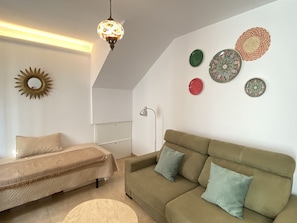 Cozy living space with a sofa, bench, and ottoman, adorned with decorative plates and a hanging lamp.