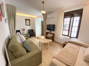 Relax in this stylish living room with a comfortable sofa, a small table, and a TV mounted on the wall.