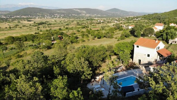 A white house with a red roof surrounded by lush greenery and a swimming pool. - Holiday Home Jadrić  (Dicmo)