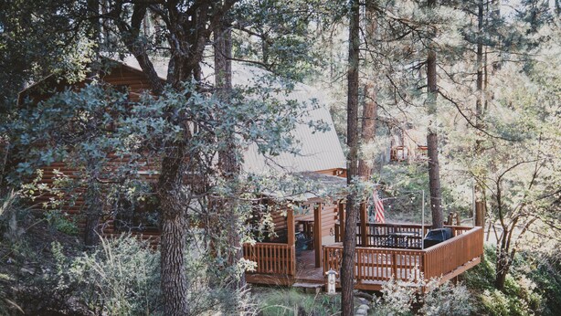 A rustic cabin with a wooden deck and a small porch, surrounded by dense forest. - State 48 Retreat Prescott Arizona (Prescott)