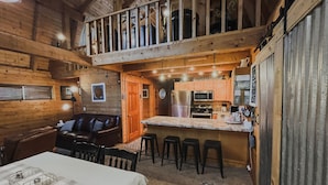 A cozy cabin interior with a dining area, a kitchen with modern appliances, and a wooden balcony. - State 48 Retreat Prescott Arizona (Prescott)