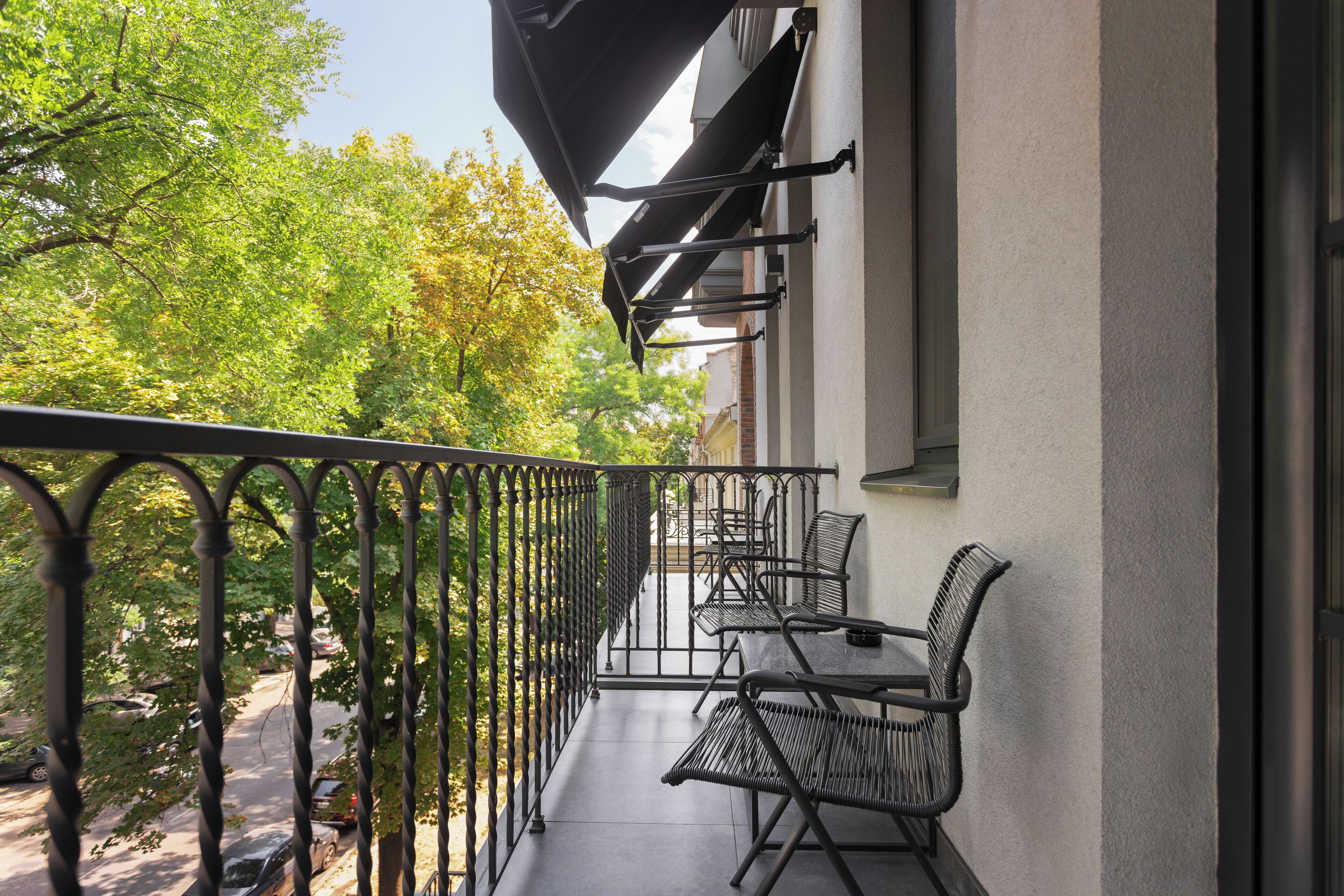 A balcony with a metal railing, a table, and two chairs.