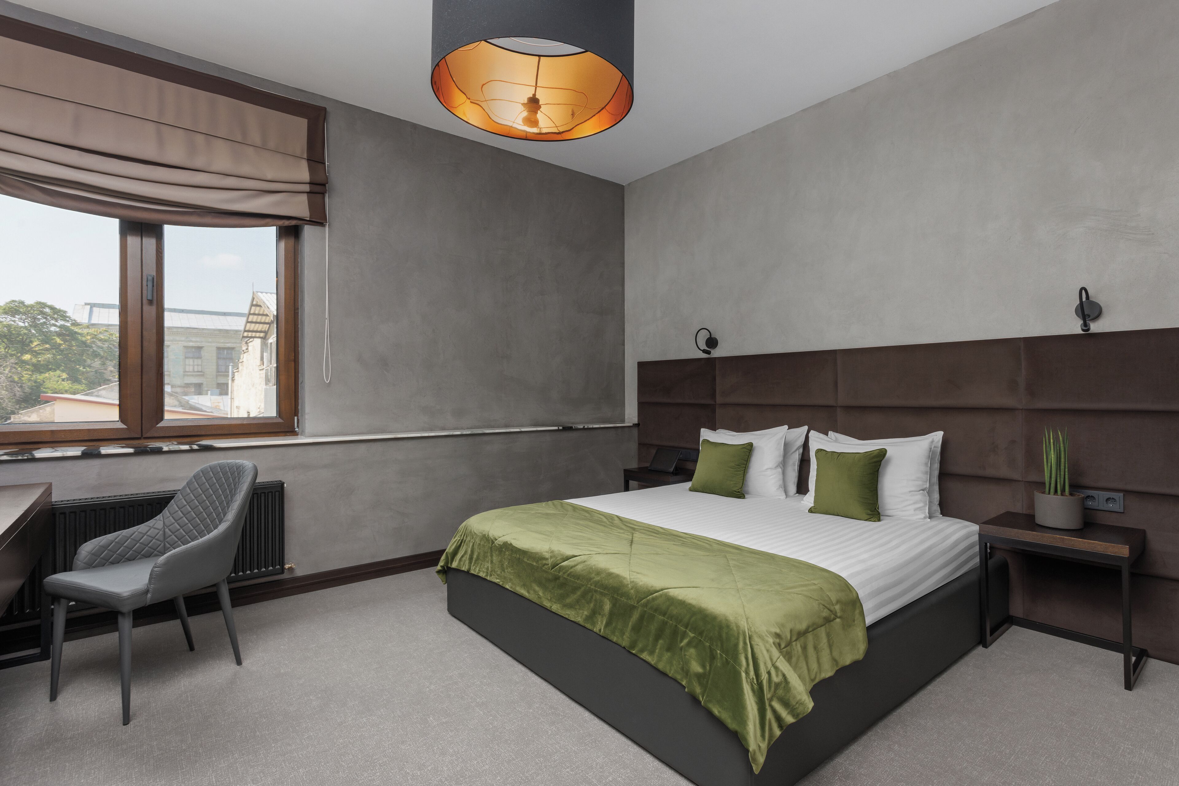 A modern bedroom with a large bed, a desk, and a chair.